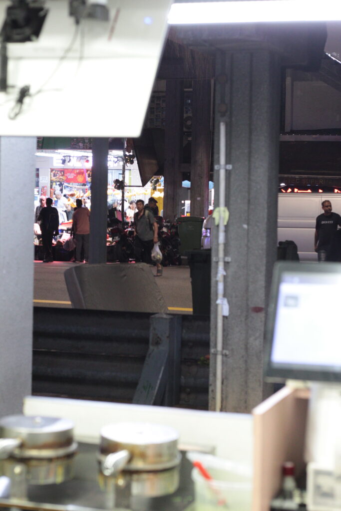 An image showing pedestrians crossing the road outside of a shop